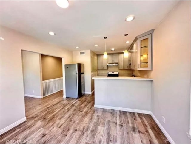 kitchen featuring dark hardwood / wood-style flooring, stainless steel refrigerator, kitchen peninsula, and decorative light fixtures