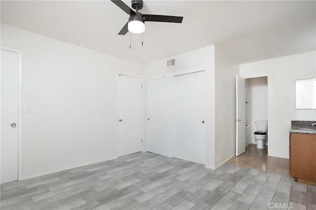 unfurnished bedroom with ensuite bathroom, sink, ceiling fan, light hardwood / wood-style floors, and a closet