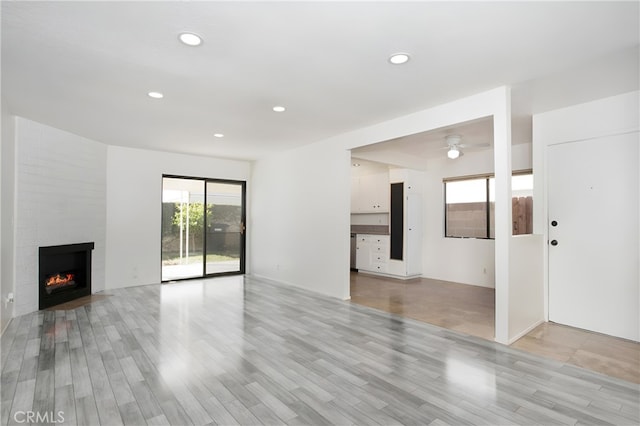 unfurnished living room featuring a fireplace, light hardwood / wood-style floors, and ceiling fan