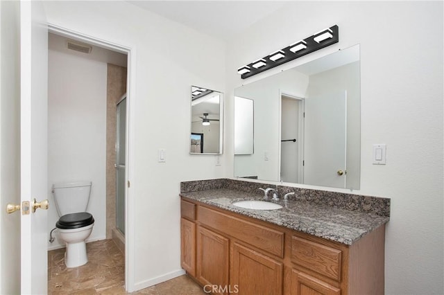 bathroom featuring ceiling fan, vanity, a shower with shower door, and toilet