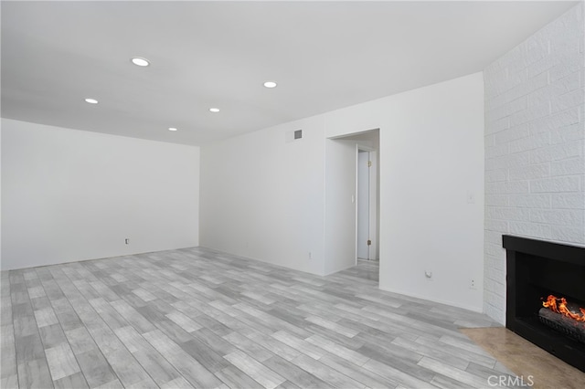 unfurnished living room with a large fireplace and light hardwood / wood-style flooring