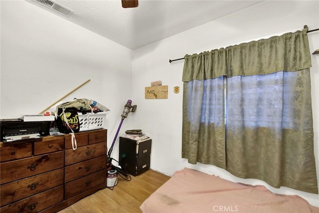 bedroom featuring ceiling fan, visible vents, and wood finished floors
