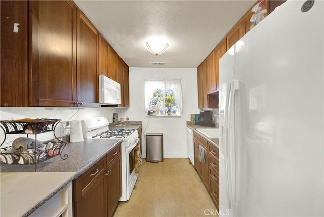 kitchen with brown cabinets, white appliances, and visible vents