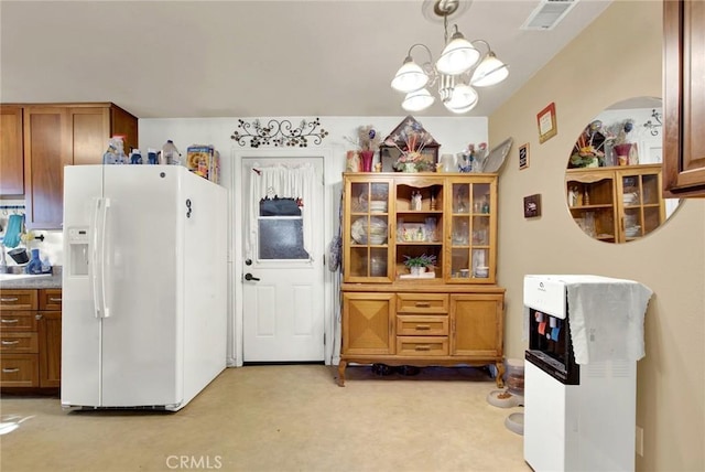 kitchen featuring white refrigerator with ice dispenser, brown cabinets, decorative light fixtures, visible vents, and an inviting chandelier