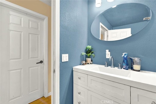 bathroom with a textured wall and vanity