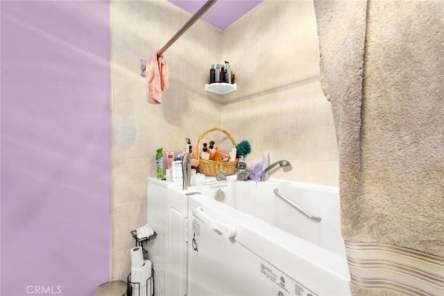 bathroom featuring a washtub and tile walls