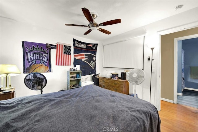 bedroom with hardwood / wood-style floors, ceiling fan, and ensuite bath