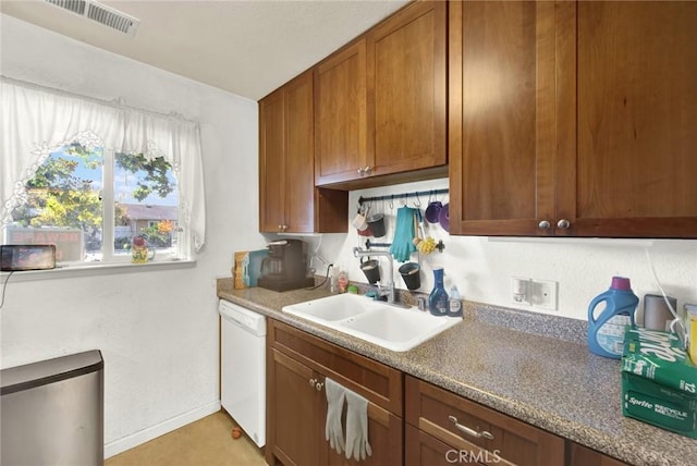 kitchen with a sink, visible vents, baseboards, brown cabinets, and dishwasher