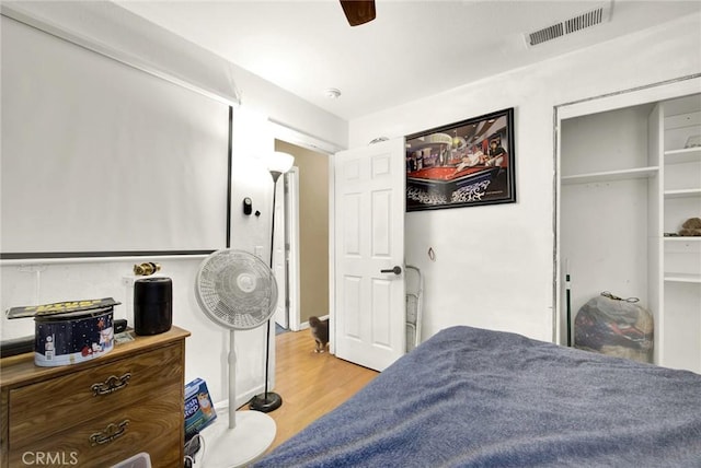 bedroom featuring ceiling fan, a closet, visible vents, and wood finished floors
