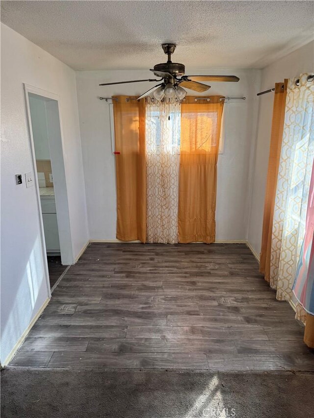 empty room with a textured ceiling, ceiling fan, and dark hardwood / wood-style floors