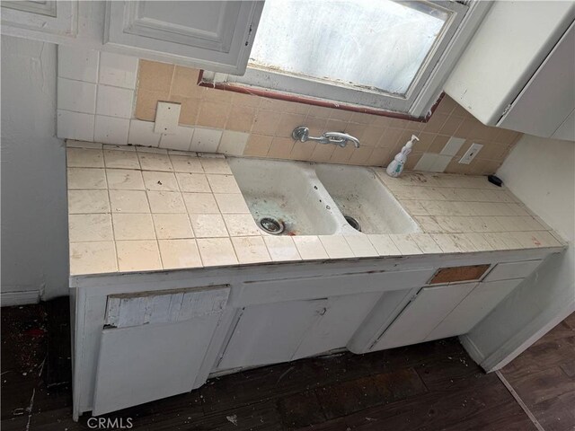 interior space featuring tasteful backsplash, sink, white cabinets, and dark wood-type flooring