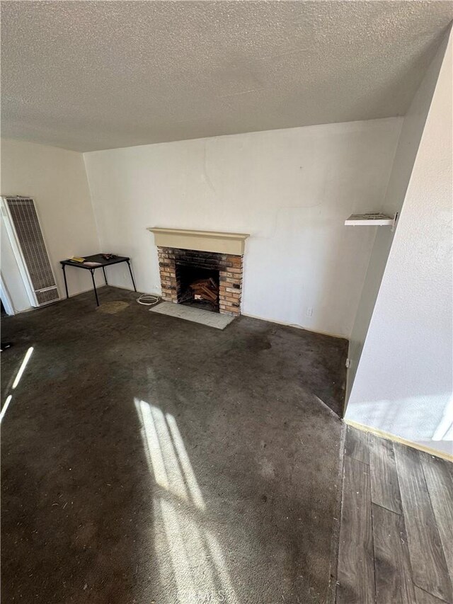 unfurnished living room with a stone fireplace, a textured ceiling, and hardwood / wood-style flooring