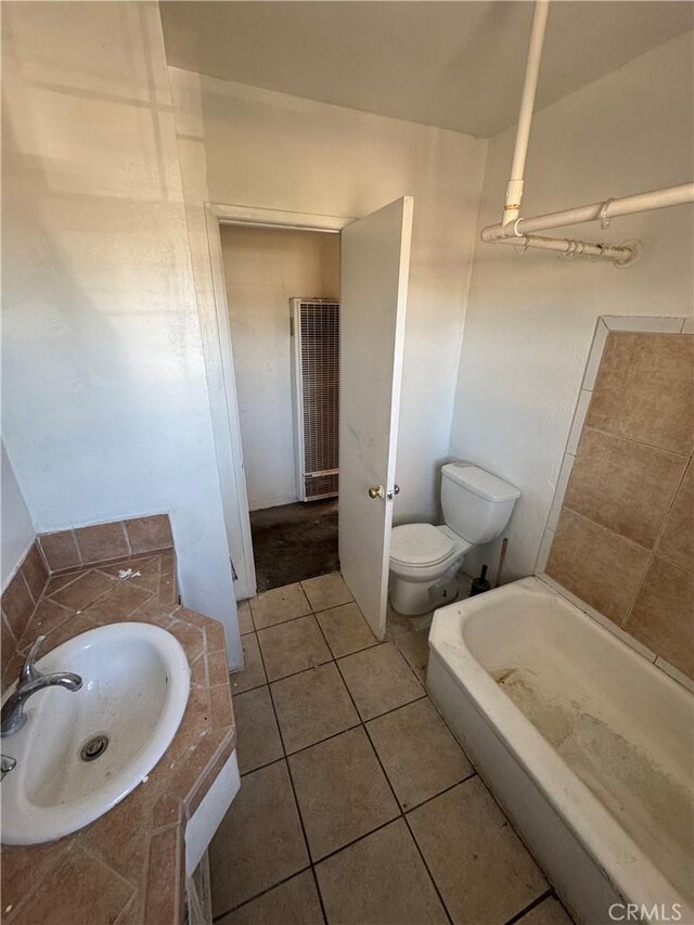 bathroom with tile patterned flooring, a washtub, toilet, and sink