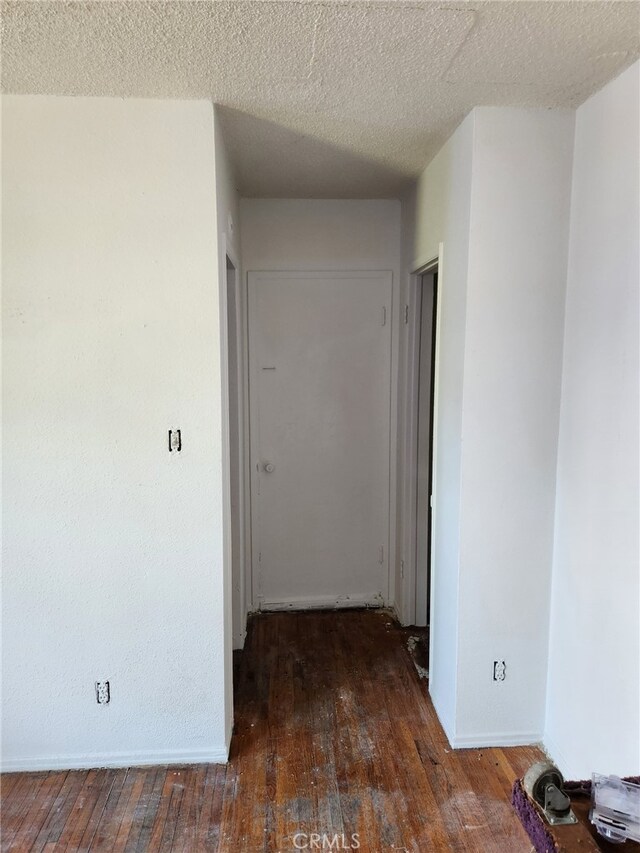 hallway featuring dark hardwood / wood-style floors and a textured ceiling