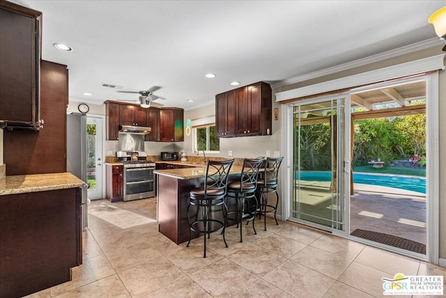 kitchen with a kitchen bar, ornamental molding, gas stove, light stone counters, and kitchen peninsula