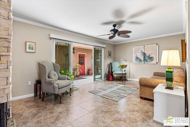 sitting room with ceiling fan, a stone fireplace, and ornamental molding