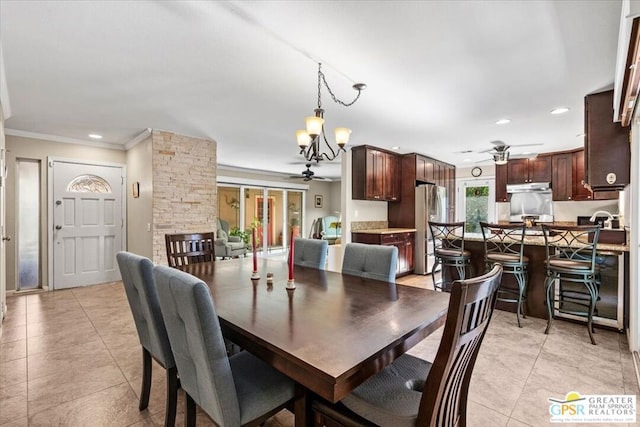 dining space with light tile patterned floors, ceiling fan with notable chandelier, and ornamental molding