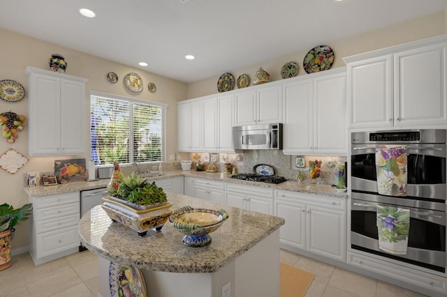 kitchen featuring white cabinets, decorative backsplash, light tile patterned floors, and stainless steel appliances