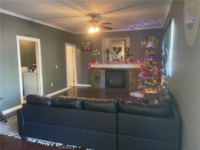 living room featuring ceiling fan, crown molding, a tile fireplace, hardwood / wood-style flooring, and washing machine and clothes dryer