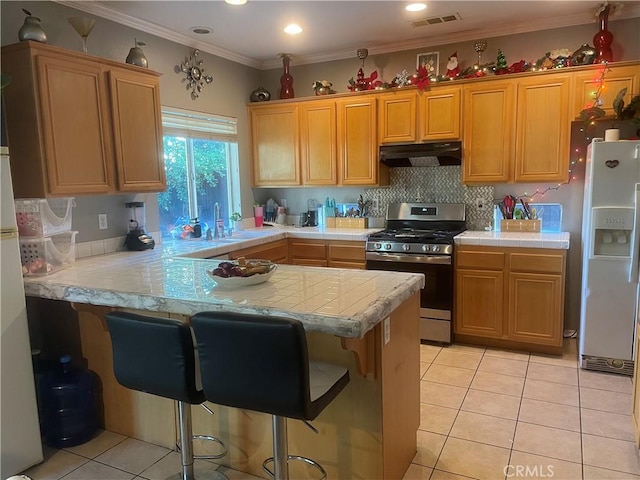 kitchen with a breakfast bar, crown molding, gas range, white fridge with ice dispenser, and kitchen peninsula