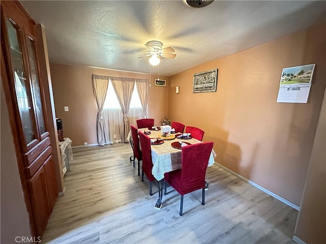 dining area with ceiling fan, light hardwood / wood-style floors, and a textured ceiling