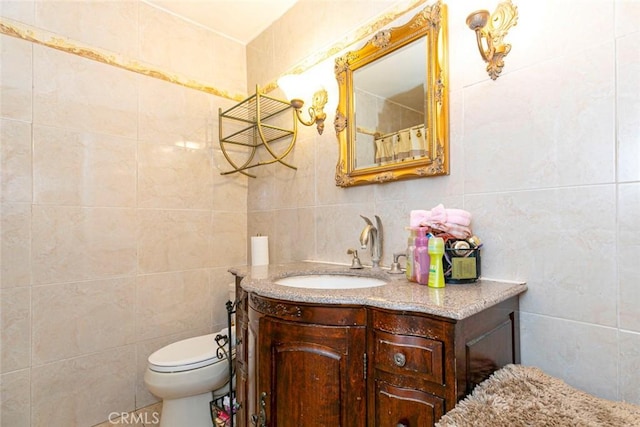 bathroom with vanity, tile walls, and toilet