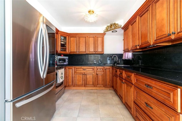 kitchen featuring dark stone counters, sink, decorative backsplash, light tile patterned floors, and stainless steel appliances