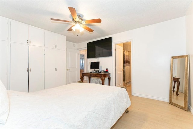 bedroom with a textured ceiling, ceiling fan, connected bathroom, light hardwood / wood-style floors, and a closet