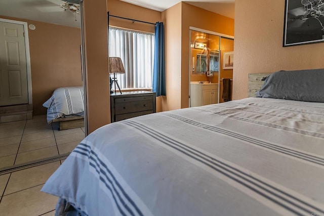 bedroom featuring tile patterned flooring, a closet, ensuite bathroom, and ceiling fan