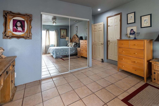 tiled bedroom featuring ceiling fan and a closet