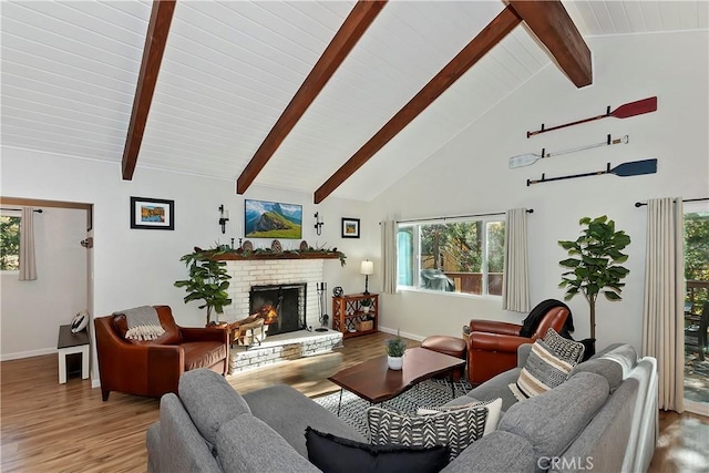 living room featuring beamed ceiling, wood-type flooring, high vaulted ceiling, and a brick fireplace