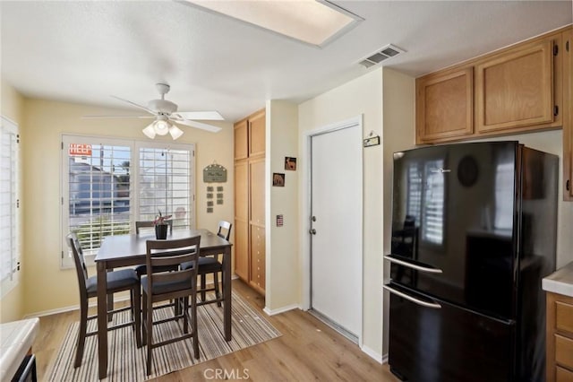 kitchen with ceiling fan, black refrigerator, and light hardwood / wood-style floors