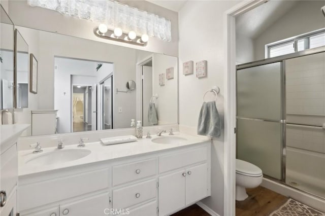 bathroom with wood-type flooring, vanity, toilet, and a shower with door