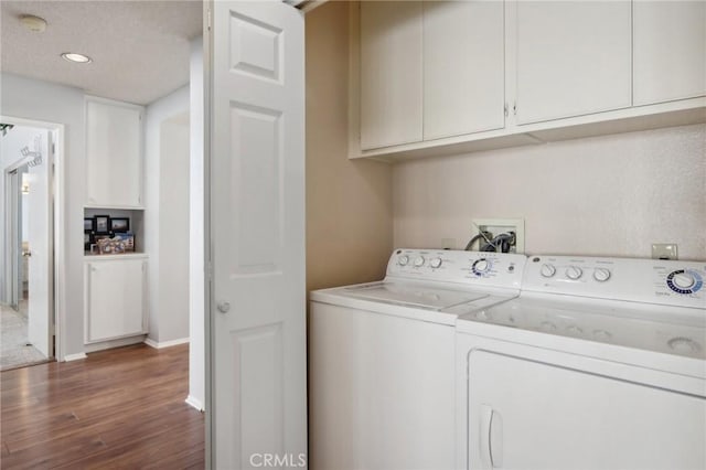 laundry room featuring cabinets, washer and dryer, and dark hardwood / wood-style flooring