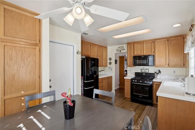 kitchen with ceiling fan, sink, black appliances, and dark hardwood / wood-style floors