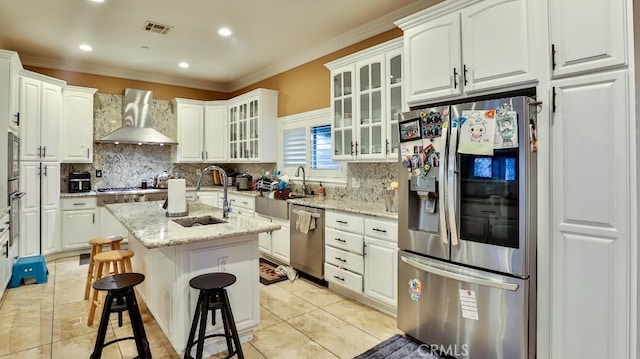 kitchen with white cabinets, a kitchen island with sink, wall chimney exhaust hood, and stainless steel appliances