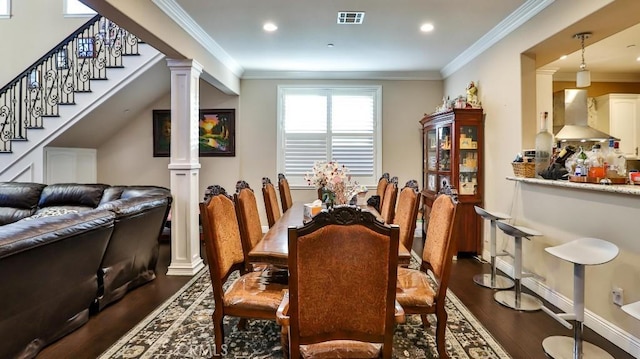 dining space featuring dark hardwood / wood-style flooring, ornate columns, and crown molding