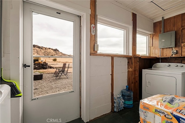 clothes washing area with a mountain view, washer / clothes dryer, electric panel, laundry area, and concrete block wall