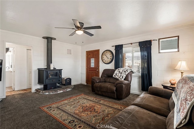 carpeted living room featuring ornamental molding, ceiling fan, and a wood stove