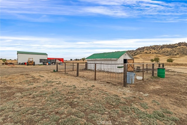 view of yard with a mountain view, an outbuilding, and a rural view