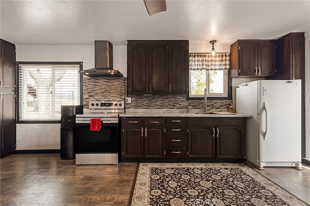 kitchen featuring white refrigerator, stainless steel range with electric cooktop, plenty of natural light, and wall chimney exhaust hood