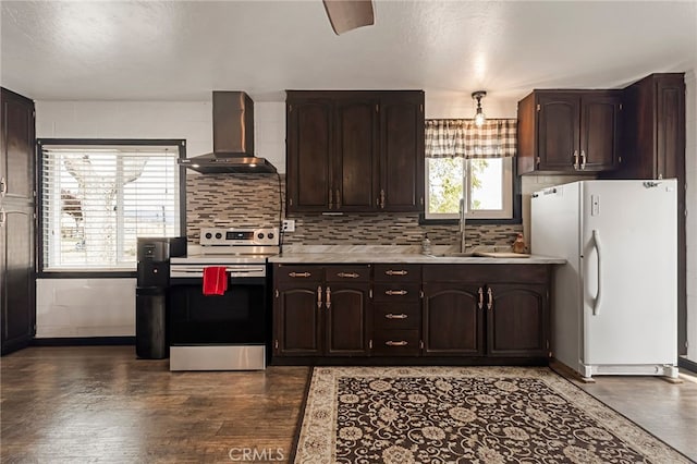 kitchen with freestanding refrigerator, wall chimney exhaust hood, light countertops, a sink, and range with electric stovetop