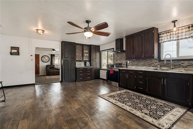 kitchen featuring stainless steel electric stove, wall chimney range hood, backsplash, dark brown cabinets, and sink