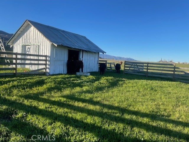 view of outbuilding with a rural view and a lawn