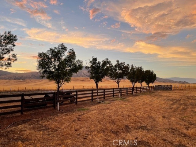 yard at dusk with a rural view and a mountain view