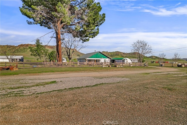 view of yard with a rural view, fence, and an outbuilding