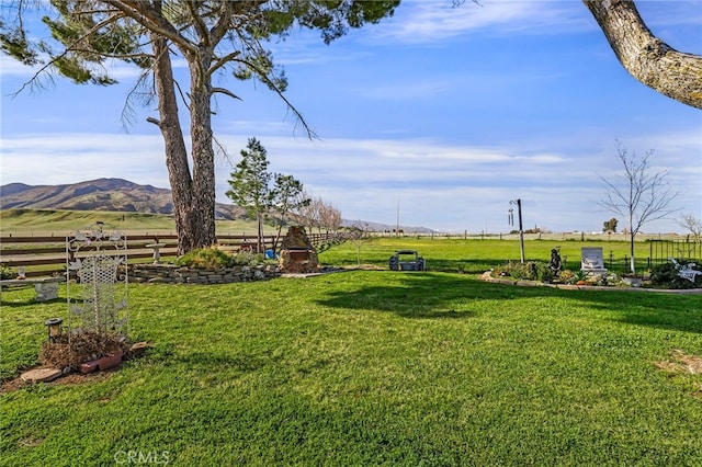 view of yard featuring a rural view, a mountain view, and fence