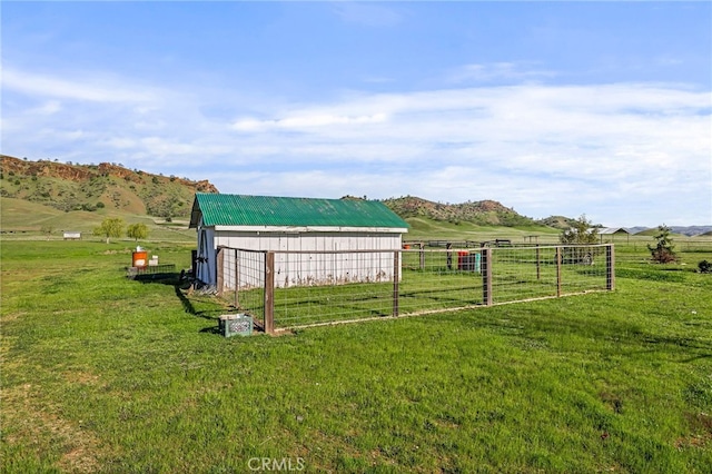 view of yard with a mountain view, a rural view, an outbuilding, a pole building, and fence