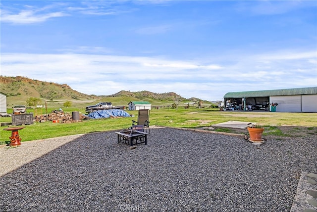 view of yard featuring a detached garage, a mountain view, an outdoor structure, and a fire pit