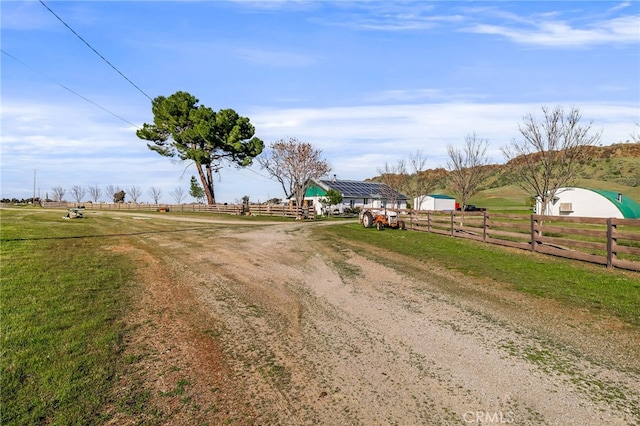 view of road with dirt driveway and a rural view